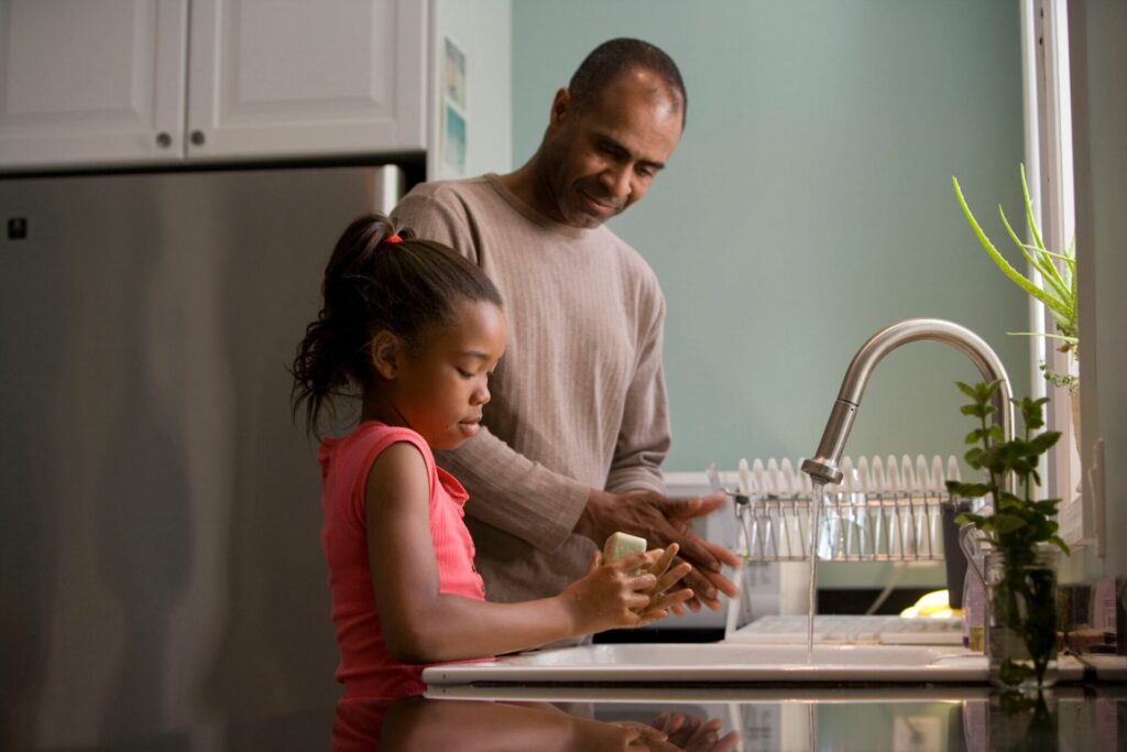child washes dishes with father while facing challenges of parent in rehab