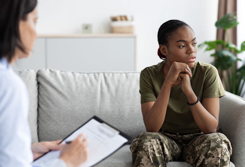 Woman in military fatigues looking off in the distance during therapy for PTSD and addiction treatment.